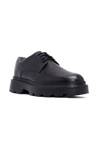 Chaussures en cuir noir avec une surface texturée, bout rond, lacets et une semelle en caoutchouc épaisse avec un motif de griffes robuste.