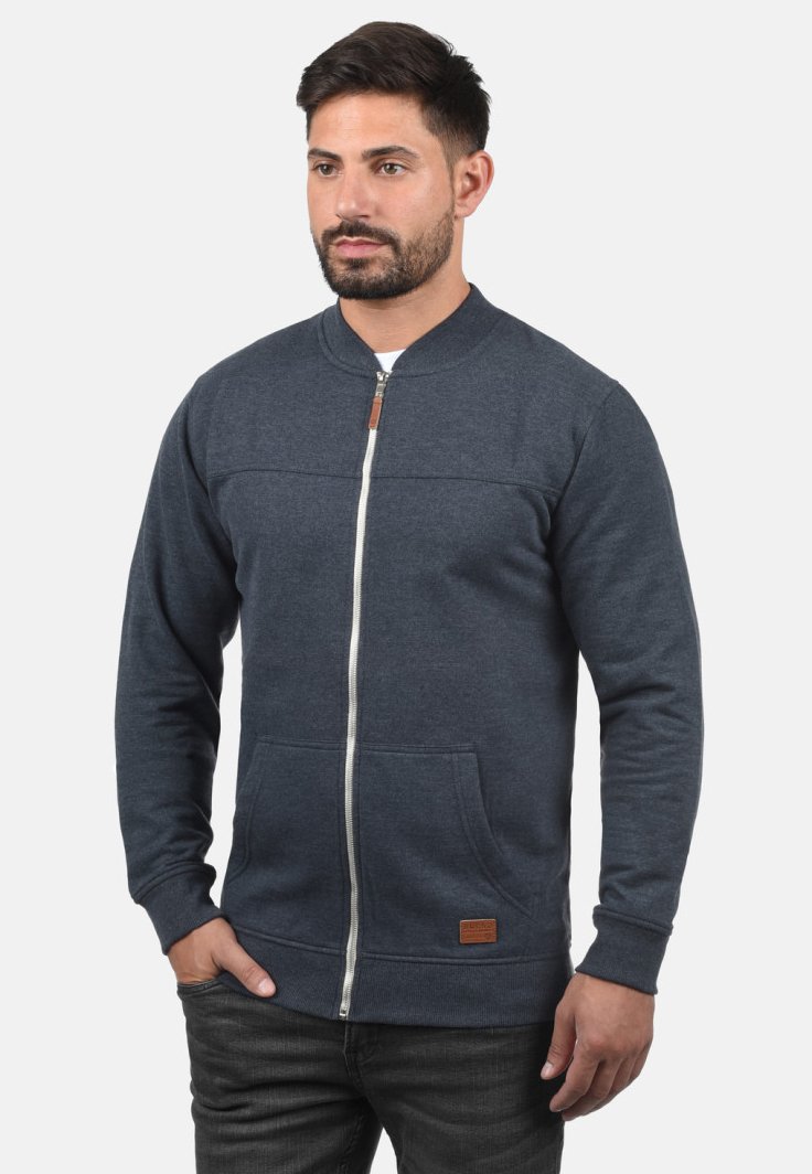 Tmavomodrá mikina na zips s okrúhlym golierom, prednými vreckami a koženým akcentom na leme. Vyrobená z mäkkej, textúrovanej látky.