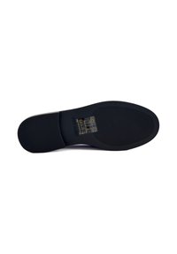 Suola di scarpa in gomma nera con texture a righe, caratterizzata da un logo del brand e simboli di cura stampati in oro. Profilo piatto, design con punta arrotondata.