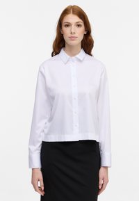 Witte katoenen knoopshirt met lange mouwen, een kraaghalslijn en een cropped zoom; stof lijkt glad en lichtgewicht.
