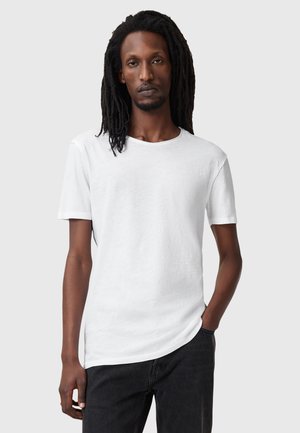 T-shirt blanc à manches courtes en coton doux, avec un col rond et une coupe décontractée, associé à un jean sombre.