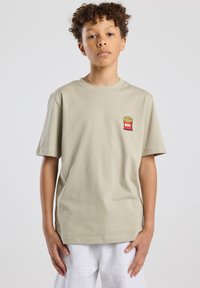 Beige cotton t-shirt with short sleeves featuring a small red and yellow fries graphic on the chest. Simple, relaxed fit design.