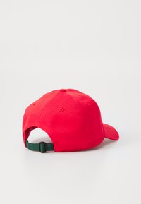 Căciulă de baseball din bumbac roșu, cu un etui curbat, curea verde ajustabilă la spate și orificii de ventilație pe laterale.