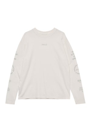 Mężczyzna ubrany w białą koszulę z długim rękawem z napisem, czarne spodenki, białe skarpetki, szare sneakersy i białe okulary przeciwsłoneczne, stojący na białym tle.