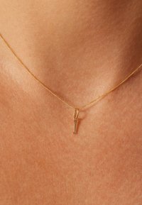 Gold chain necklace featuring a small, pendant letter "I." The chain is thin and delicate, with a smooth, shiny finish.
