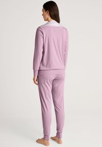 Lila gekleurde loungewear set met een lange mouwen top met een gestreepte kraag en bijpassende broek, gemaakt van een zachte, lichte stof.