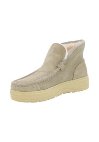 Bota de tobillo beige de ante con forro acolchado, costuras estilo mocasín y suela gruesa texturizada beige para uso casual en invierno.