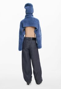 Sinise tekstuuriga kudumiga lühike jakk kõrge kraega, kombineeritud tumedate laiade teksapükstega. Komplekti iseloomustab avatud seljaga disain.