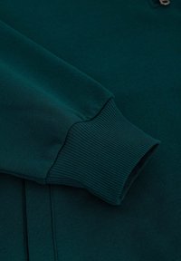 Donkergroen sweatshirt met een ribbelmanchet, voorzien van een gladde textuur en subtiele stikdetails. Ritssluiting bij de hals voor sluiting.