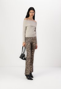 Beige off-the-shoulder ribbed sweater paired with leopard print flared pants. Black pointed-toe heels and a small black handbag complete the look.