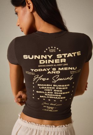 Femme portant un T-shirt foncé avec le menu et les spécialités "Sunny State Diner" imprimés au dos en texte clair.