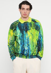 Pulóver élénk zöld és kék mintával, galléros kialakítással és bordázott szegéllyel. Puha anyagból készült, ideális mindennapi viselethez.