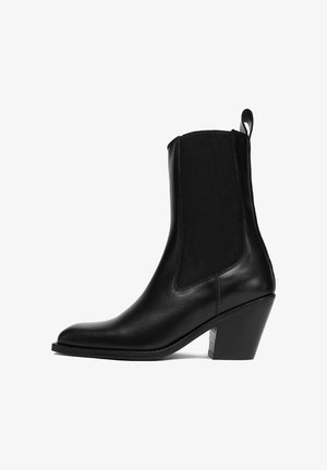 Schwarzer Leder-Stiefelette mit elastischen Seitenteilen, Schlaufe, spitzer Zehe und Blockabsatz.