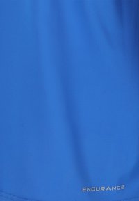 Blåt stof med subtil tekstur og ordet "ENDURANCE" printet med små hvide bogstaver nær den nederste kant.