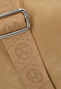 Tasche aus taupefarbenem Wildleder mit glatter Textur, ausgestattet mit einer silberfarbenen Metall schnalle und einem Trageriemen, der mit kreisförmigen Logo-Mustern geprägt ist.