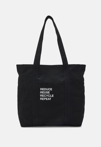 Černá plátěná taška s dvěma uchy, na přední kapse s bílým textem "REDUCE REUSE RECYCLE REPEAT". Jednoduchý, obdélníkový design.