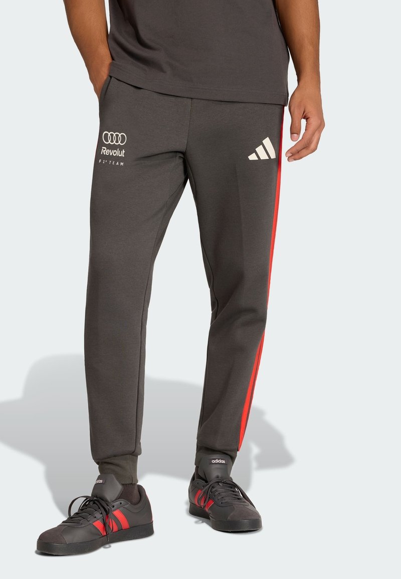 Grijze sportbroek met rode zijstrepen. Logo's van Audi en Adidas op de voorkant gedrukt, met een taps toelopend ontwerp en elastische boorden.