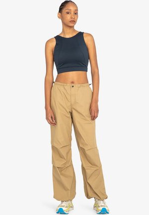 Marineblaues, ärmelloses, tailliertes Top, kombiniert mit hellbeigen, locker sitzenden Cargo-Hosen mit elastischem Bund und Taschen.