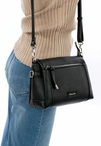 Black leather crossbody bag with a zippered front pocket, silver hardware, and adjustable strap. Smooth texture with a rectangular shape.