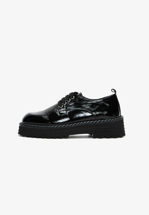 Scarpe stringate in vernice nera con una suola nera spessa e testurizzata, dotata di un'accortezza simile a una corda lungo il bordo. Design classico e finitura liscia.