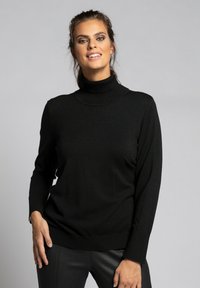 Schwarzer Rollkragenpullover mit langen Ärmeln, geribbelten Bündchen und lockerer Passform, aus einem weichen Stoff gefertigt, vor einem grauen Hintergrund präsentiert.