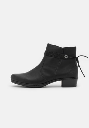 Bottine noire à talon bas avec des détails de bride latérale et un nœud noué à l'arrière, fabriquée en cuir lisse.