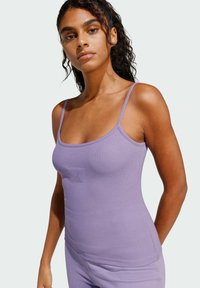 Svetlo fialový rebrovaný top s tenkými ramienkami, ktorý má na prednej strane malé embosované logo. Mäkká textúra a priliehavý strih.