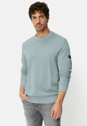 Lyseblå crewneck-sweatshirt med struktureret stof, ribstrikkede ærmekanter og kant. Har en lille logopatch på venstre ærme.