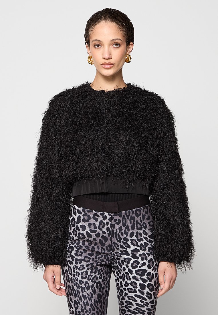 Giacca nera corta realizzata in materiale peloso con maniche larghe. Abbinata a pantaloni a vita alta con stampa leopardata e fascia elastica nera in vita.