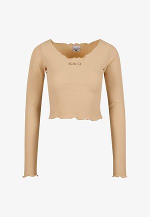Bež ribakujuline pika varrukaga crop top, millel on sakilise kaeluse ja äärega viimistlus. Keskel on tikand "KANI". Pehme tekstuur.