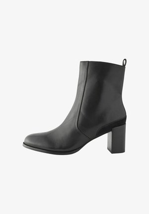 Juodos odinės aulinės botai su smailiu nosiu, lygiu paviršiumi ir cilindriniu bloku. Yra užpakalinis užtrauktukas, kuris palengvina apsiauvimą.