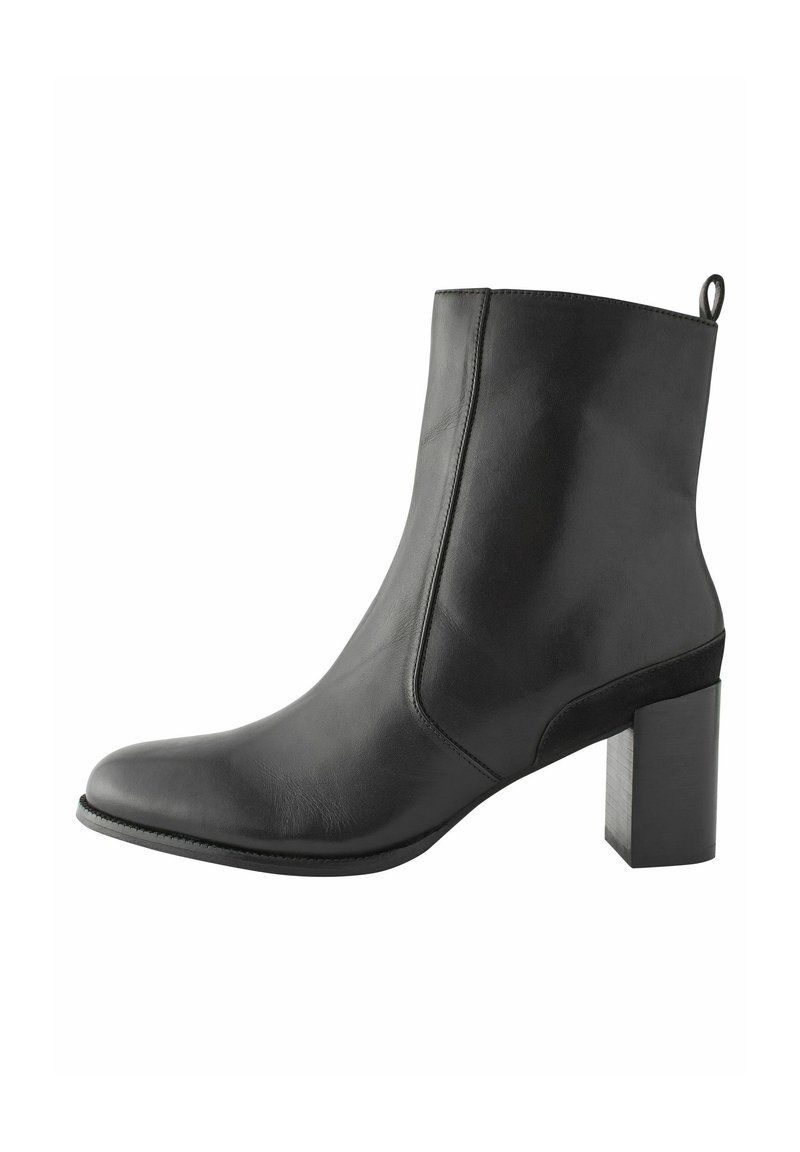 Bottine en cuir noir avec un bout pointu, texture lisse et un talon bloc cylindrique. Dotée d'une petite languette à l'arrière pour faciliter l'enfilage.