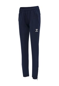 Granatowe spodnie sportowe z elastycznym pasem, kieszeniami po bokach, zamkami przy kostkach i białym logo Hummel na lewym udzie.