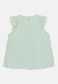 Mintgrønn bluse med blomstermønster, med blondebesetning ved skuldrene og glidelås i ryggen. Lett stoff og løs passform.