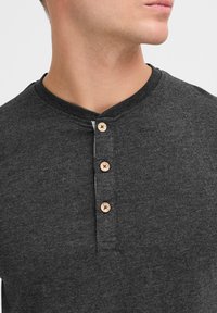 Donkergrijze henley-shirt van textuurstof met een ronde halslijn en vier houten knopen aan de voorkant.