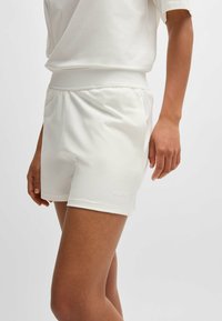 Vita shorts i mjukt material, med resårmidja och en diskret präglad "HUGO"-logotyp på den nedre vänstra fållen.