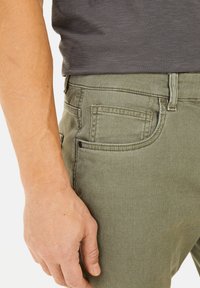 Groene katoenen broek in een mengsel met een textuurafwerking. Voorzien van standaardzakken en een slim fit ontwerp, getoond met een grijs shirt dat gedeeltelijk zichtbaar is.