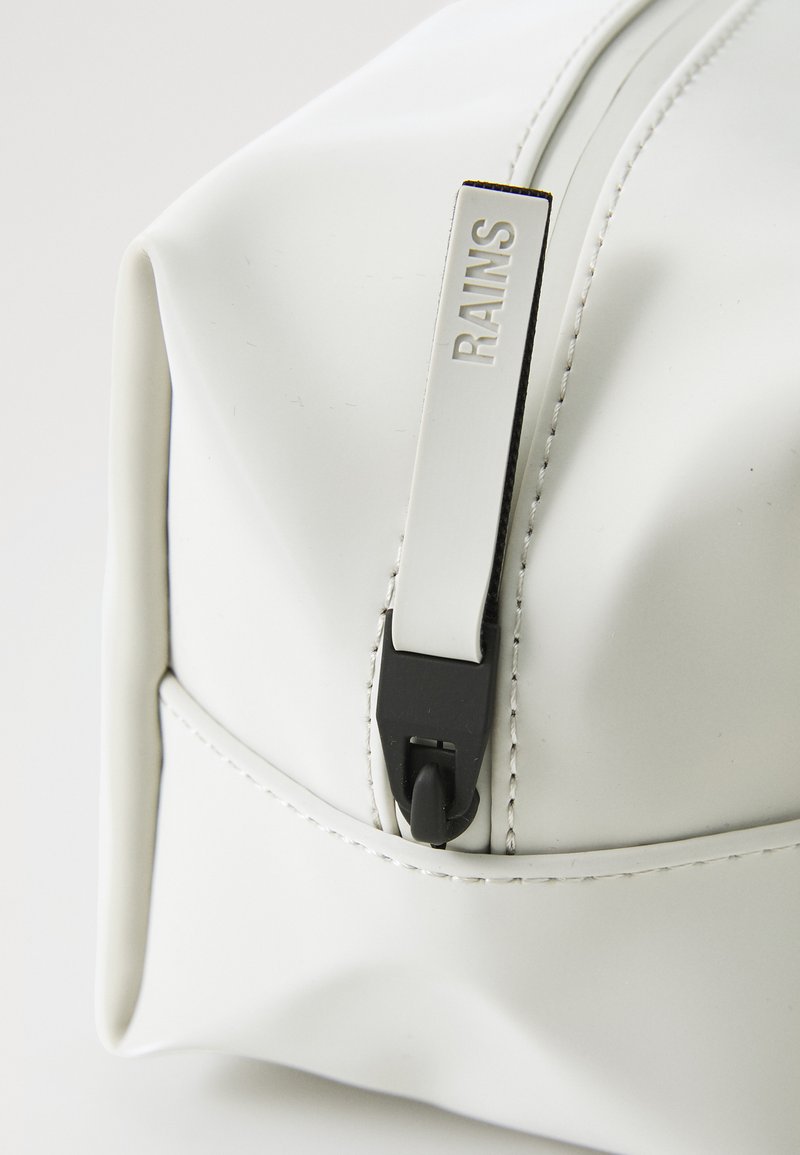 Biały wodoodporny worek z czarnym zamkiem i srebrnymi detalami, z subtelnymi ściegami i prostokątnym kształtem.