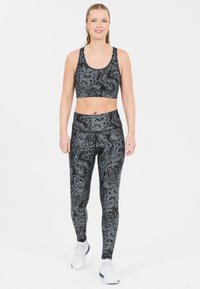 Svart och gråmönstrad sportbh och leggings set, tillverkat av elastiskt tyg, med en åtsittande design och hög midja för stöd.