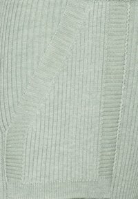 Ribbed light green textile featuring textured panels, contrasting horizontal and vertical stitches, and subtle sheen in the fabric.