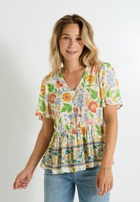 Top peplum floral en colores pastel con mangas cortas, escote en V y un dobladillo con volantes que presenta patrones decorativos en azul y verde.