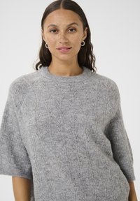 Lichtgrijs gebreid sweater met een gemêleerd patroon, een ronde hals en korte mouwen. Zachte stof en delicate, subtiele details.