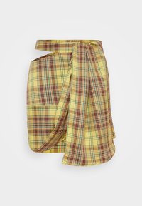 Yellow plaid wrap skirt featuring shades of brown and green, with a draped design and a tie belt. Smooth fabric with a textured finish.