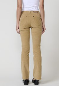 Beige corduroy flared broek met een middelhoge taille, met twee achterzakken en een leren logo-label bij de tailleband.