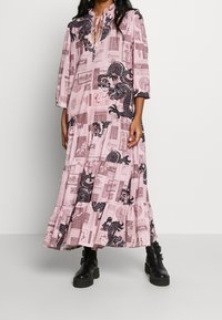 Růžové maxi šaty s černým potiskem draka a vintage kolážovými vzory. Šaty mají vrstvený lem a kulatý výstřih se zavazováním.