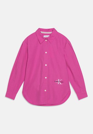 Camisa de manga larga de color rosa brillante con cuello, botones blancos y pequeño logo de Calvin Klein Jeans en la parte inferior delantera derecha.