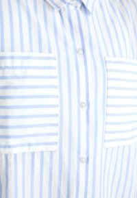 Modrobíle pruhovaná košile se dvěma našitými kapsami, zapínáním na knoflíky a límečkem, vyrobená z lehké látky, má vertikální pruhy.