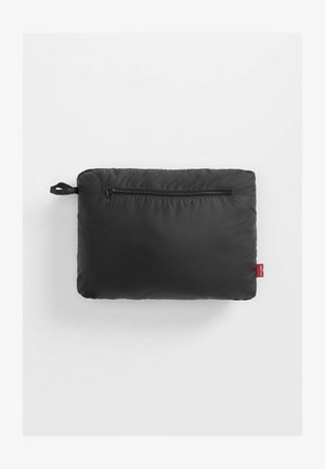 Cojín rectangular negro con una textura suave, que cuenta con un cierre de cremallera y una pequeña etiqueta roja en un lado.