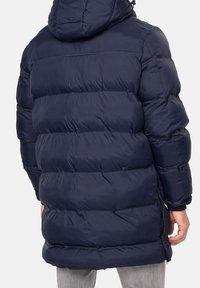 Marineblaue Daunenjacke mit Kapuze, ausgestattet mit einem gesteppten Design, Reißverschlusstaschen an den Seiten und elastischen Bündchen. Glattes, glänzendes Material mit lockerer Passform.