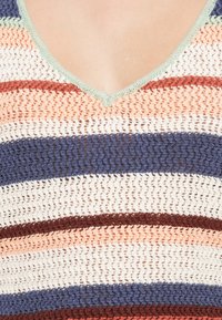 Gestricktes Tanktop mit gestreiften Mustern in Creme, Marine, Rost, Pfirsich und Grün. Besitzt einen tiefen V-Ausschnitt und eine offene Struktur.